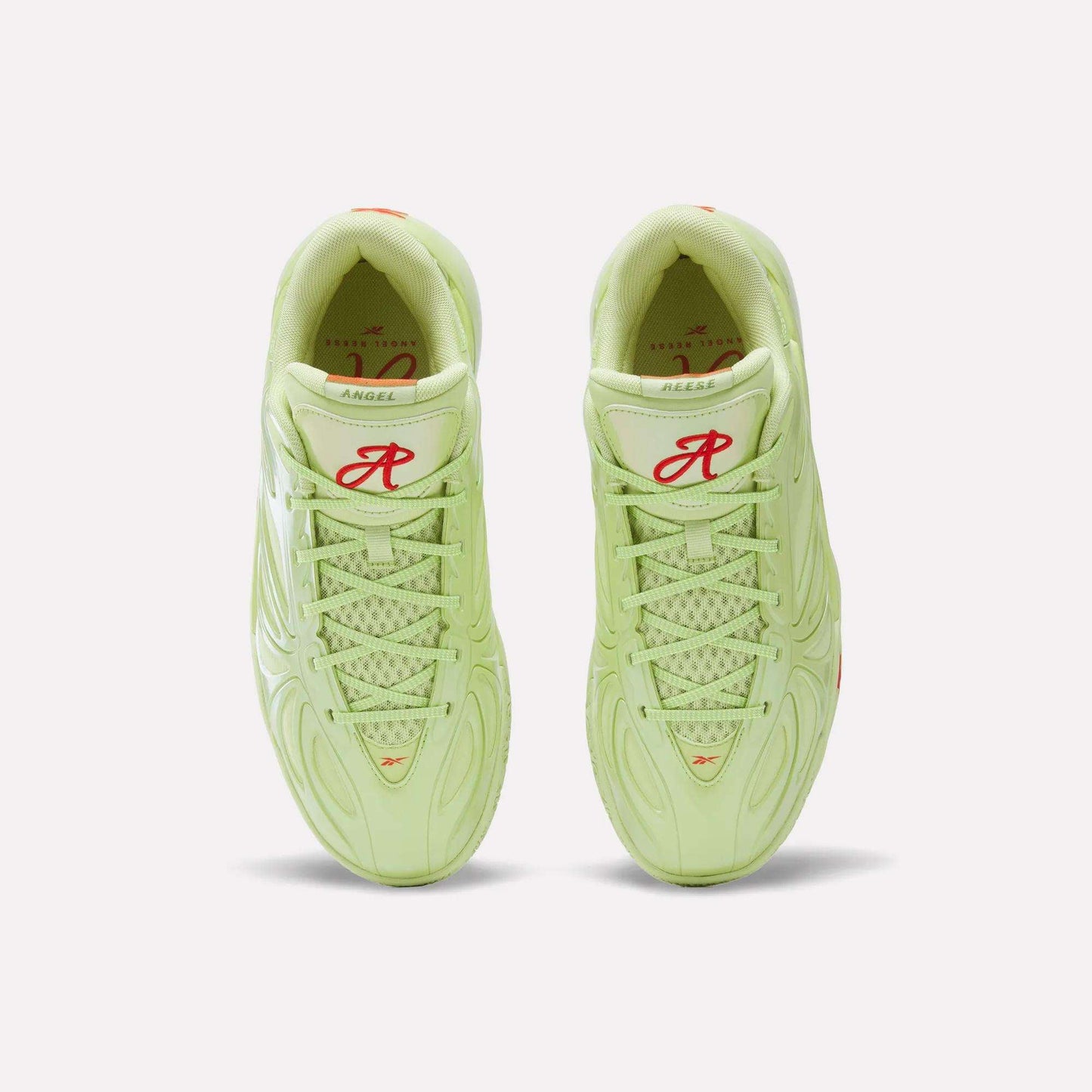 Top view of a pair of light green Reebok Angel Reese 1 Basketball Shoes with red R and logo on the tongues, white soles, patterned mesh uppers, and Reebok Energy Return System tech displayed against a white background.