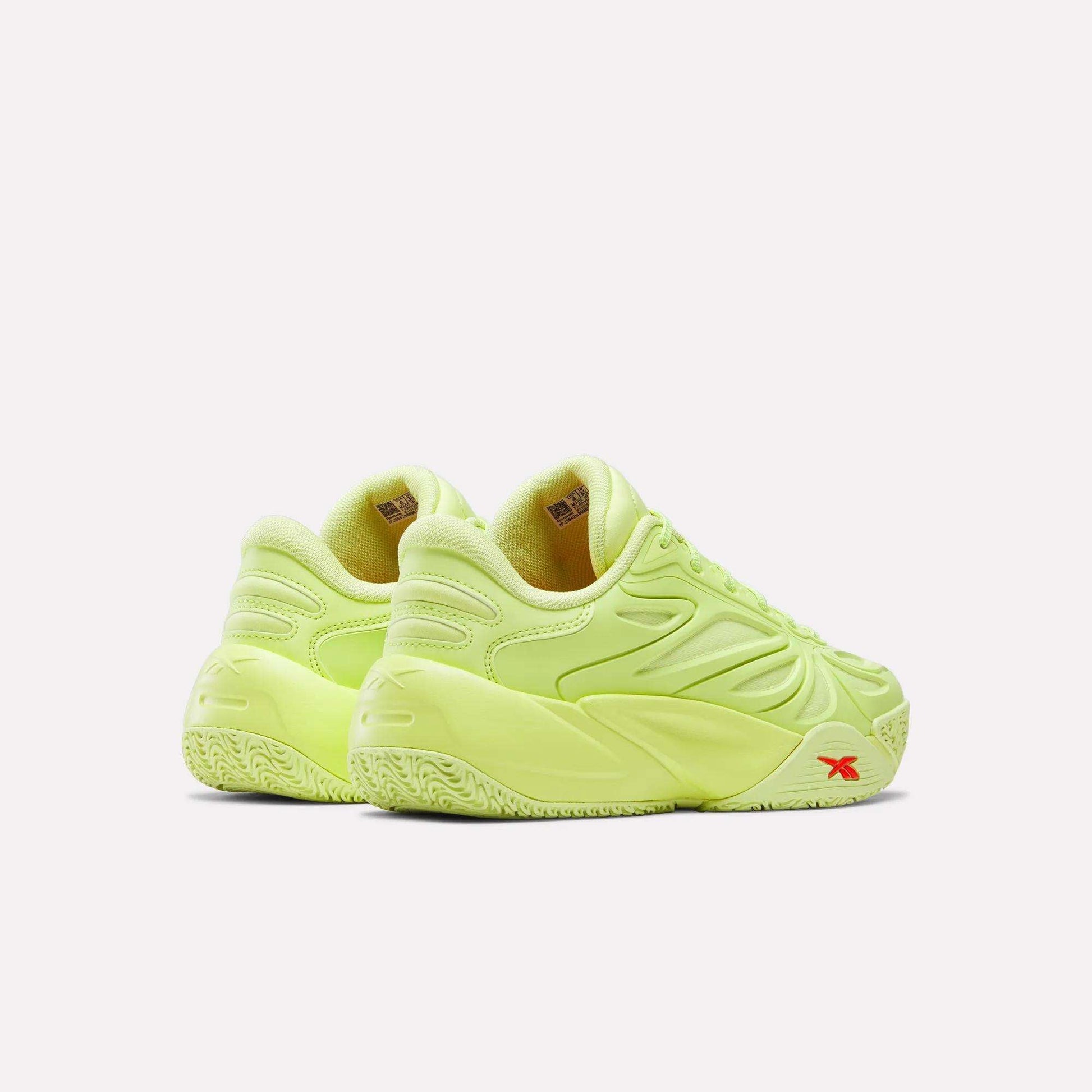 The Reebok Angel Reese 1 Shoes - Big Kids in neon yellow feature textured soles, curved detailing, and a small red logo by the heel, shown from the back and side on a white background.