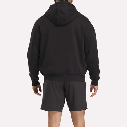 A person faces away from the camera, wearing a Men's Reebok x F45 Training Relaxed Hoodie in black against a plain white background.