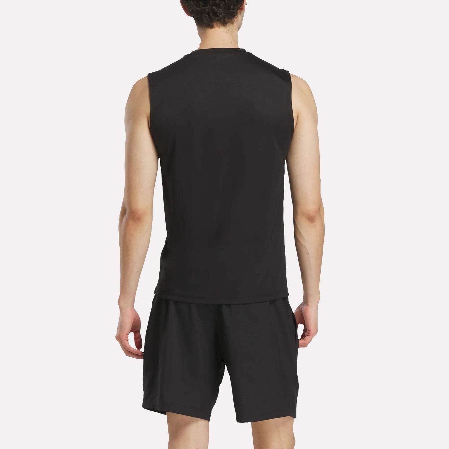 A person wearing a Men's Reebok x F45 Training Tank Top and black shorts stands facing away, displaying the back of their outfit against a plain white background—ideal attire for high-intensity workouts or F45 Training sessions.