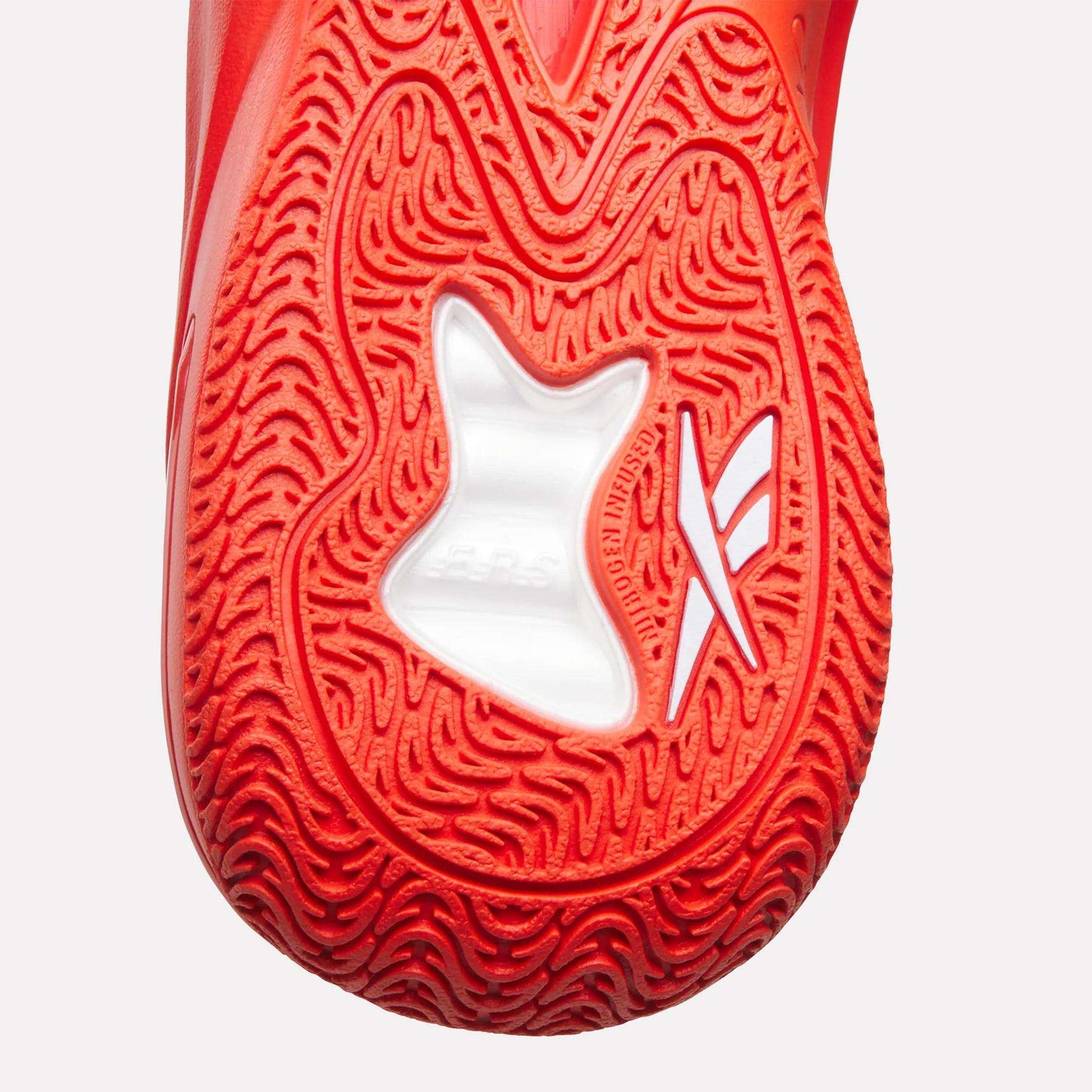 Close-up of the red textured sole of the Reebok Angel Reese 1 Basketball Shoes, featuring a white star-shaped cutout and stylized markings, and highlighting the Energy Return System for optimal support.