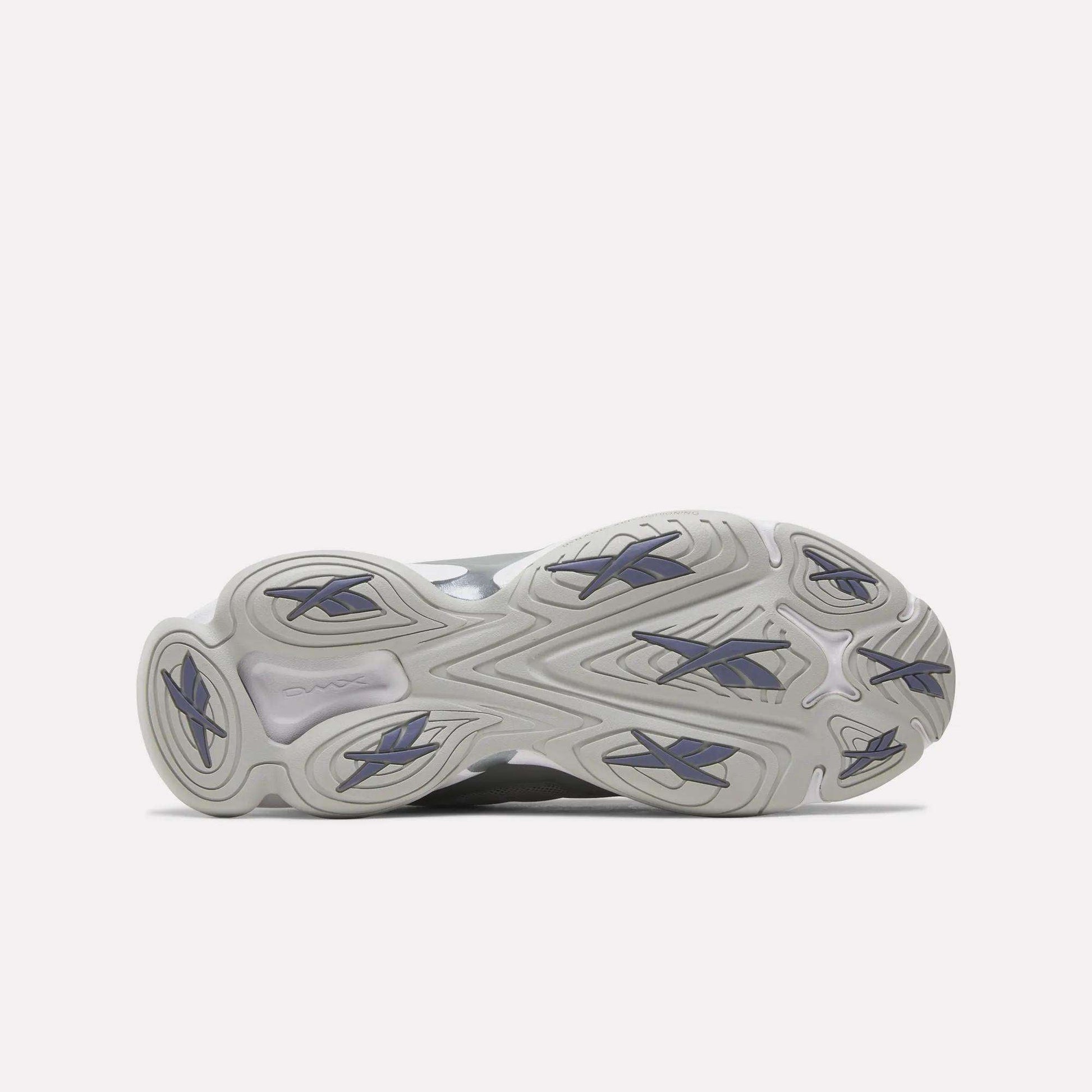 The image displays the outsole of the Reebok DMX Series 3000 Shoes, showcasing a wavy, textured light gray pattern with dark blue rubber traction accents against a white background. These shoes are engineered for comfort and enhanced grip, featuring innovative DMX moving air technology.
