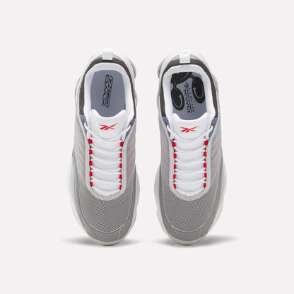 Top view of a pair of Reebok DMX Series 3000 Shoes in grey with white laces, red accents, and white soles, featuring DMX moving air technology for enhanced comfort, set against a plain light background.