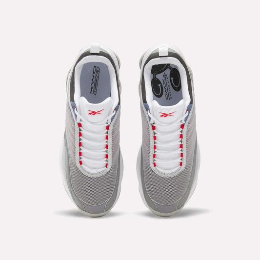 Top view of a pair of Reebok DMX Series 3000 Shoes in grey with white laces, red accents, and white soles, featuring DMX moving air technology for enhanced comfort, set against a plain light background.