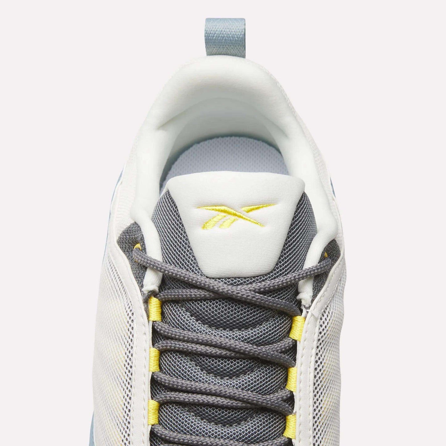 Top view of Reebok DMX Series 3000 Shoes in white and grey with yellow accents, dark grey laces, DMX moving air technology for comfort, and a yellow Reebok logo on the tongue, set against a light background.