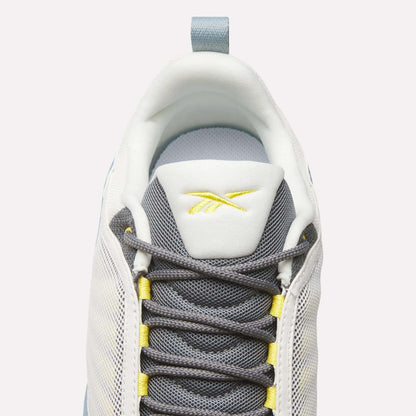 Top view of Reebok DMX Series 3000 Shoes in white and grey with yellow accents, dark grey laces, DMX moving air technology for comfort, and a yellow Reebok logo on the tongue, set against a light background.