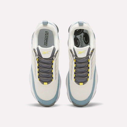 Top view of white Reebok DMX Series 3000 Shoes with gray and blue accents, gray laces, and yellow details on the tongue and lace holes. Designed for comfort with DMX moving air technology, shown on a plain light background.