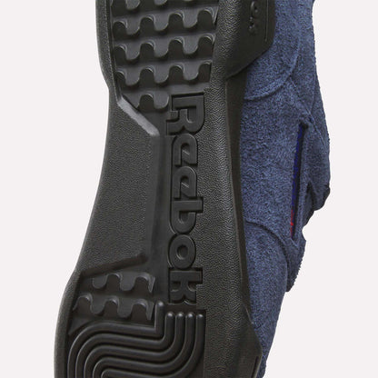 Close-up of the sole on Reebok Workout Plus Shoes, featuring the embossed Reebok logo in black rubber, distinctive tread patterns, and hints of blue fabric upper—reflecting classic 1980s fitness style.
