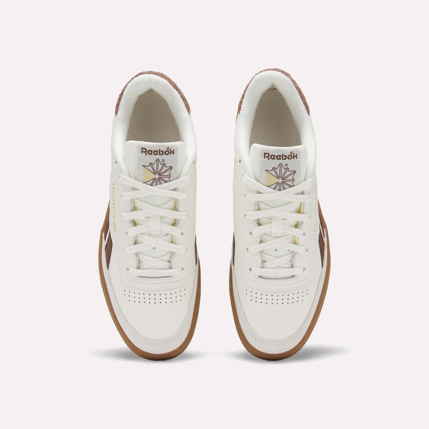 Top view of a pair of Men's Club C Revenge Vintage Shoes by Reebok, in white leather with brown soles and accents, showcasing the Reebok logo and starburst design on the tongue against a plain light background.