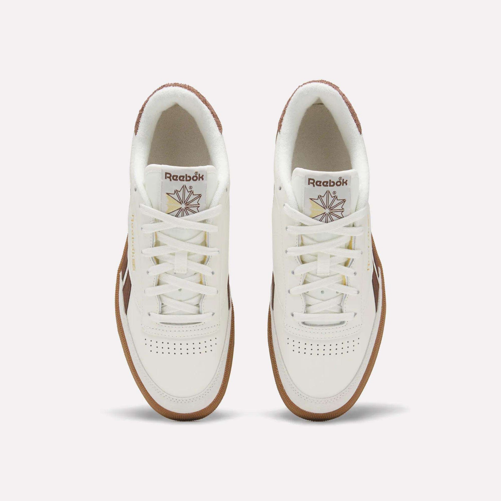 Top view of a pair of Men's Club C Revenge Vintage Shoes by Reebok, in white leather with brown soles and accents, showcasing the Reebok logo and starburst design on the tongue against a plain light background.
