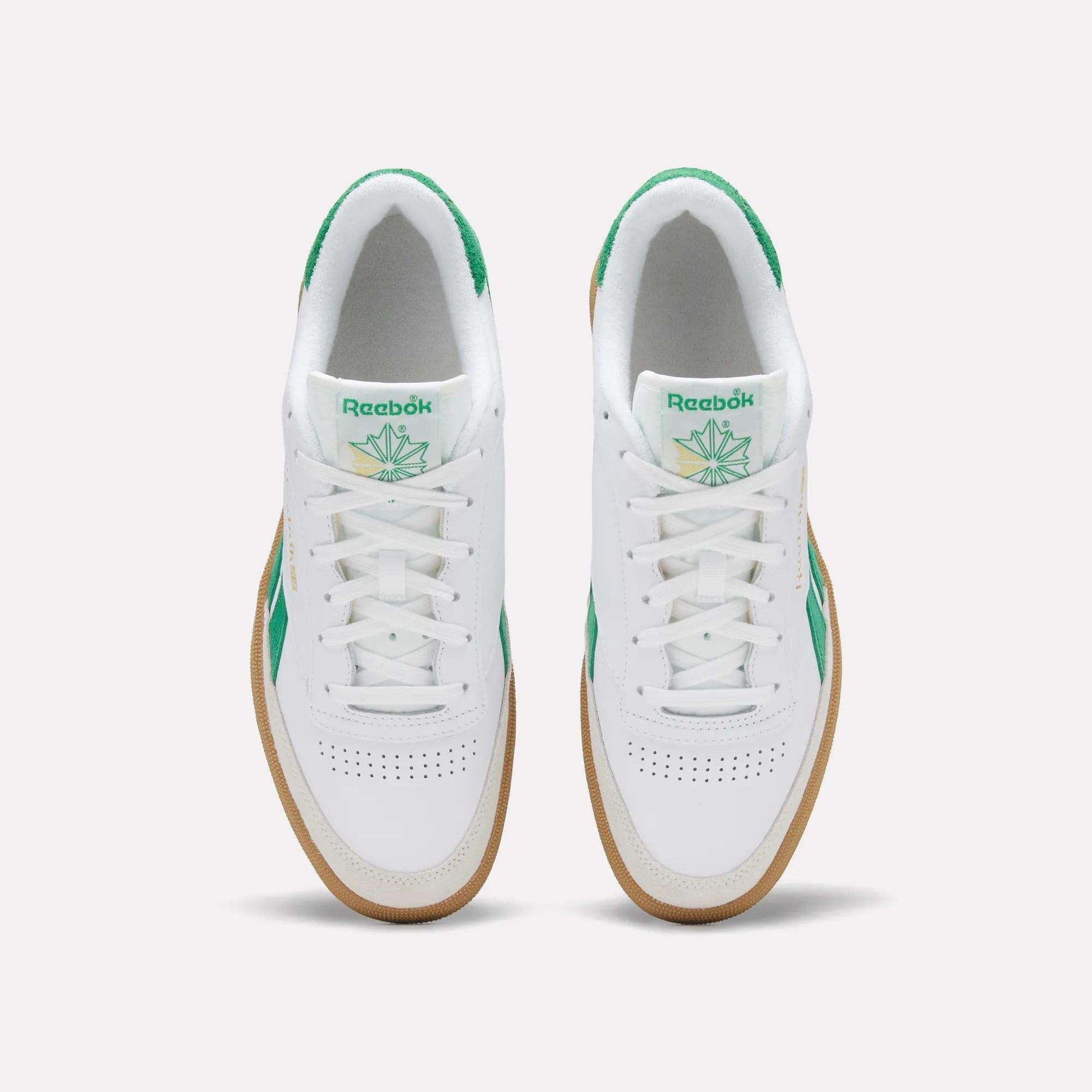 Top view of a pair of Reebok Men's Club C Revenge Vintage Shoes in white, featuring green accents, heritage branding on the tongue, and gum soles, placed side by side on a plain light background.
