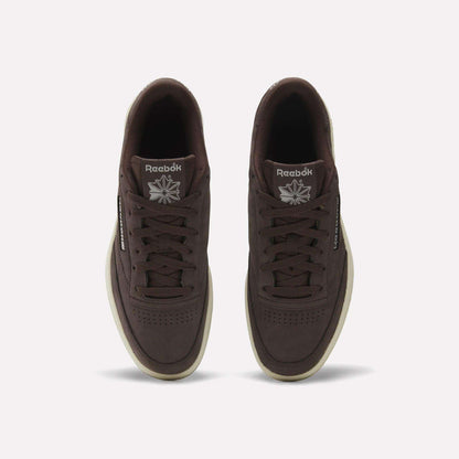 Top view of Reebok Men's Club C 85 Shoes in dark brown nubuck leather with off-white soles and visible logos on the tongue and side, displayed against a plain white background.