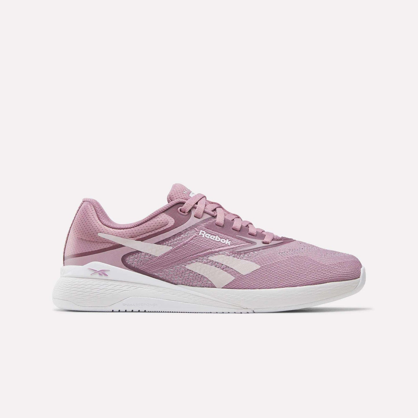 The Nano X5 Women's Training Shoes by Reebok feature a pink design with light pink accents, a white Reebok logo, dual-density midsole for comfort, and a white sole, shown against a plain white background.