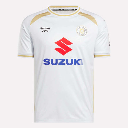 The Men's MK Dons Home Jersey by Reebok is a white football shirt with gold trim, a bold red Suzuki logo on the front, and a circular team crest on the left chest—an iconic piece for Milton Keynes fans.