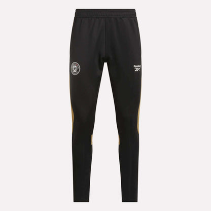 Reebok Men's MK Dons Travel Pants feature an elastic waistband, white logo and crest on the thighs, and yellow accents below the knees—ideal men's travel pants for dedicated football fans.