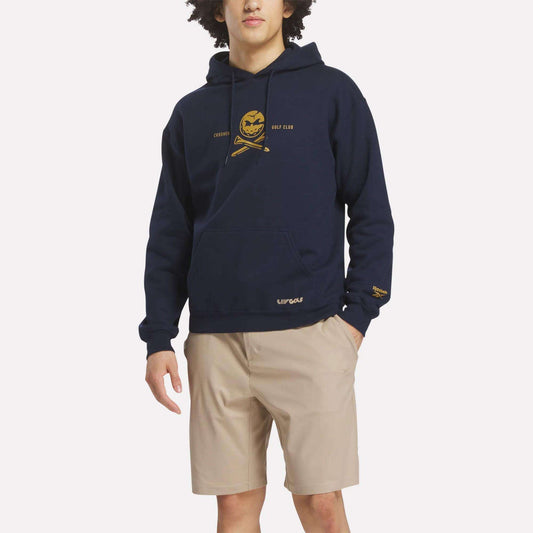 A person wears the Reebok Men's Crushers Hoodie in navy with a yellow chest graphic and text, paired with beige shorts against a plain white background.