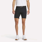 A man models Reebok Men's Favorite Golf Shorts 8.5", paired with a white polo, black belt, and white sneakers against a plain white background; only his body from the shoulders down is shown.