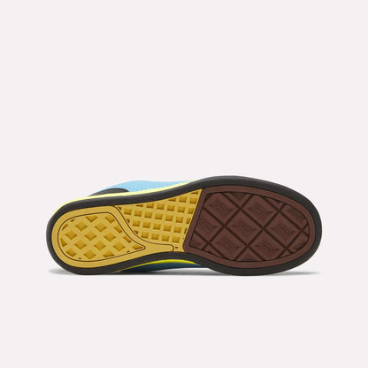 The underside of the Reebok x Icecream Board Flip Shoes by Reebok, showcasing a yellow and brown rubber sole with a textured grid pattern for traction, is set against a plain white background.