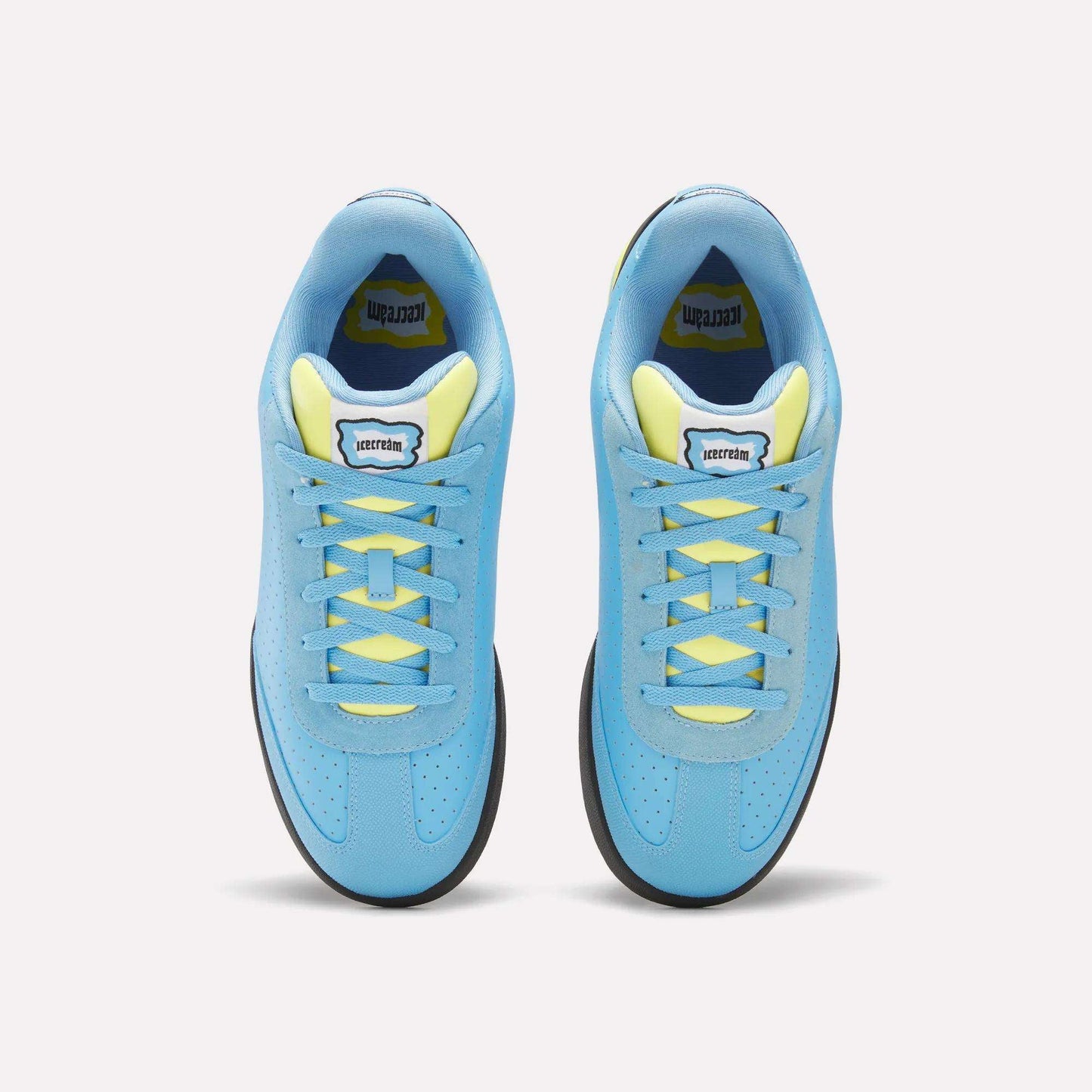 A pair of Reebok x Icecream Board Flip Shoes in blue with yellow laces and inner lining, seen from above on a light background. Early-2000s style sneakers feature a rectangular tongue label with black text.
