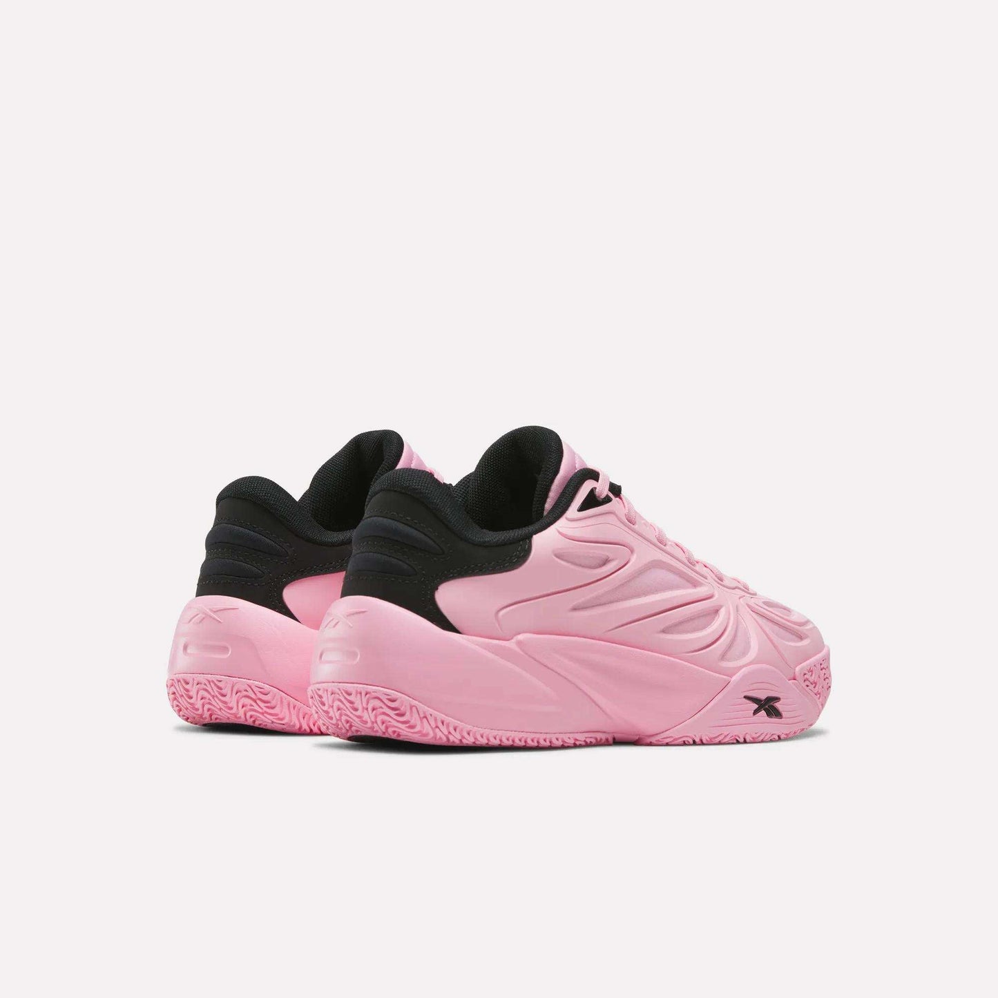 A pair of Reebok Angel Reese 1 Shoes - Big Kids in pink and black, featuring textured pink soles and embossed detailing, are displayed at an angle on a plain white background.