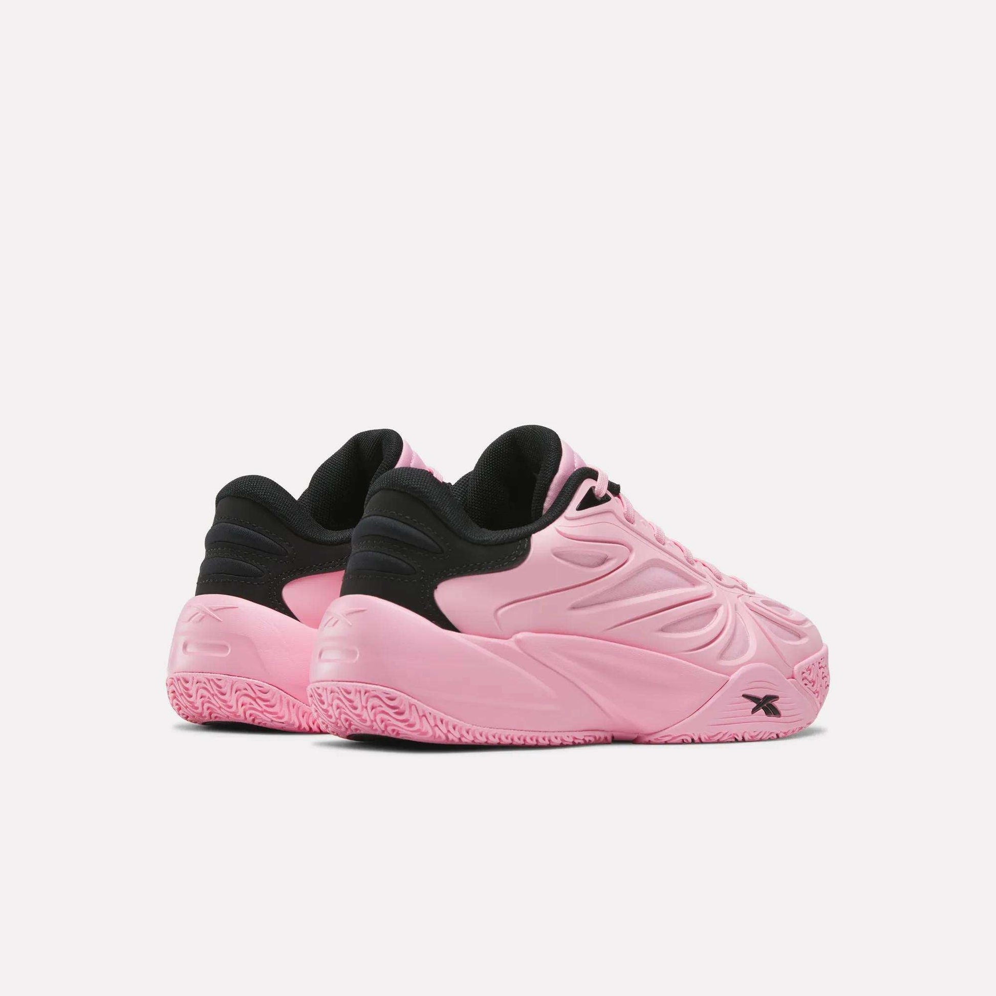 A pair of Reebok Angel Reese 1 Shoes - Big Kids in pink and black, featuring textured pink soles and embossed detailing, are displayed at an angle on a plain white background.