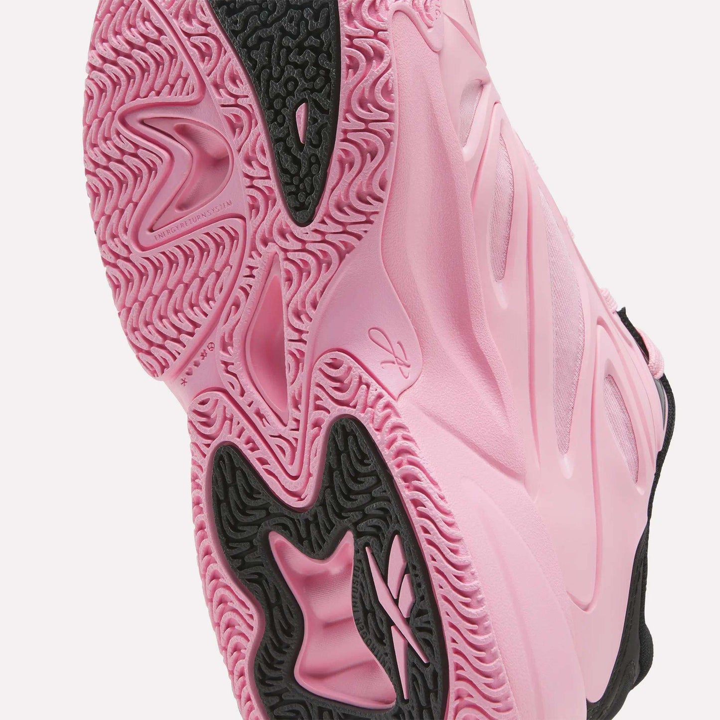 Close-up of the pink and black sole of the Reebok Angel Reese 1 Shoes for big kids, showcasing textured patterns, grooves, and a visible Reebok logo—highlighting the shoe’s grip and standout design details. Perfect for young players seeking performance and style in their basketball shoes.
