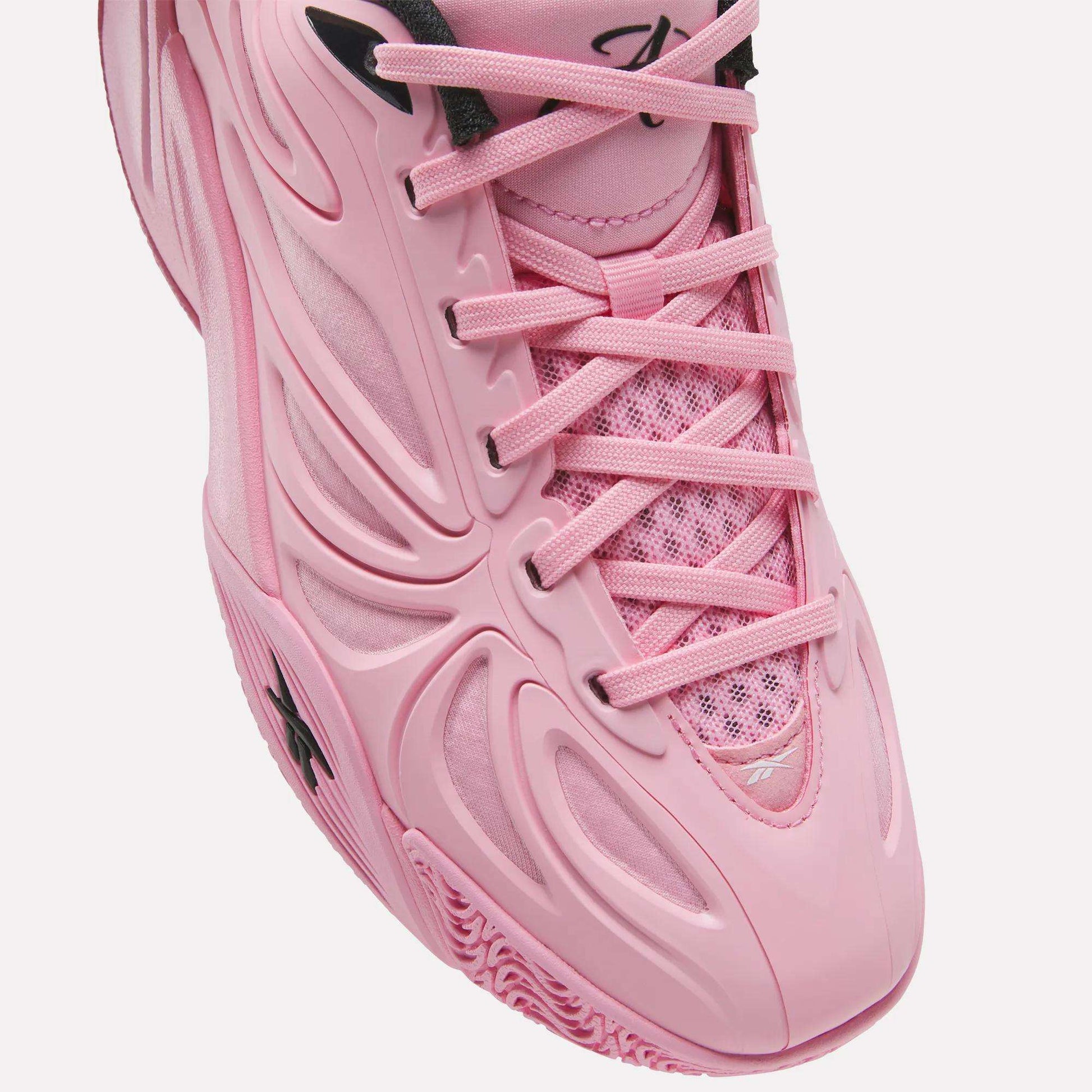 Close-up of the Reebok Angel Reese 1 Shoes for big kids—pink athletic sneakers with a textured sole, mesh tongue, and plastic overlays, featuring black lace holes and a small logo on the toe. This stylish design is inspired by kids basketball shoes and offers both comfort and performance.