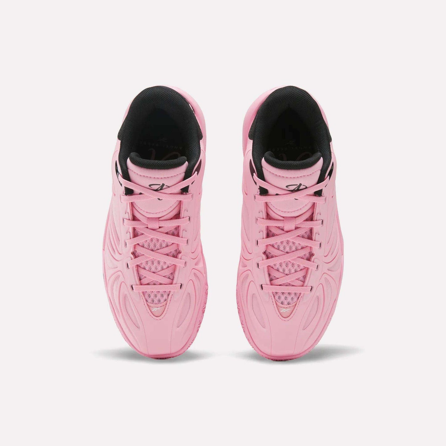 A pair of vibrant Angel Reese 1 Shoes - Big Kids by Reebok, these pink athletic sneakers with black interior linings are shown from above, highlighting the detailed patterns on the uppers and laced fronts—perfect basketball shoes for young athletes seeking both style and performance.