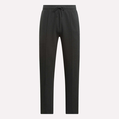 Men's Club Sport Textured Pants by Reebok feature a black textured design, slim tapered fit, and drawstring waistband with front panel seams and tapered legs, shown against a plain white background.