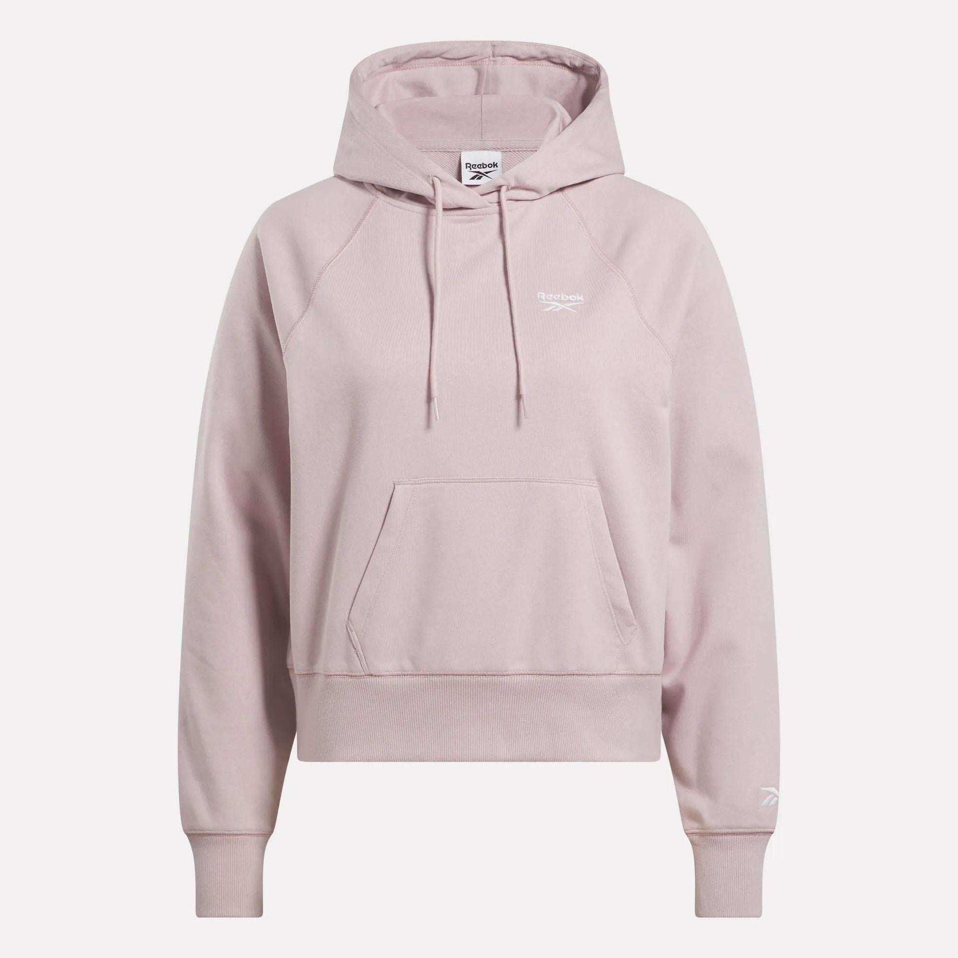 The Women's Small Vector Cropped Hoodie by Reebok comes in light pink French terry, featuring a front pocket, drawstrings, and white logos on the chest and sleeve. Shown against a plain white background.
