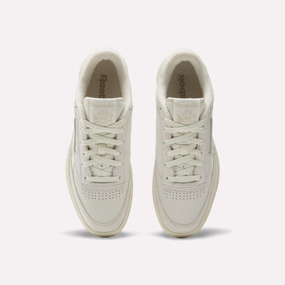 Top view of men's Reebok Club C Revenge Shoes in cream, featuring white laces, perforated nubuck leather toes, and visible Reebok logos on the tongues, set on a plain white background.