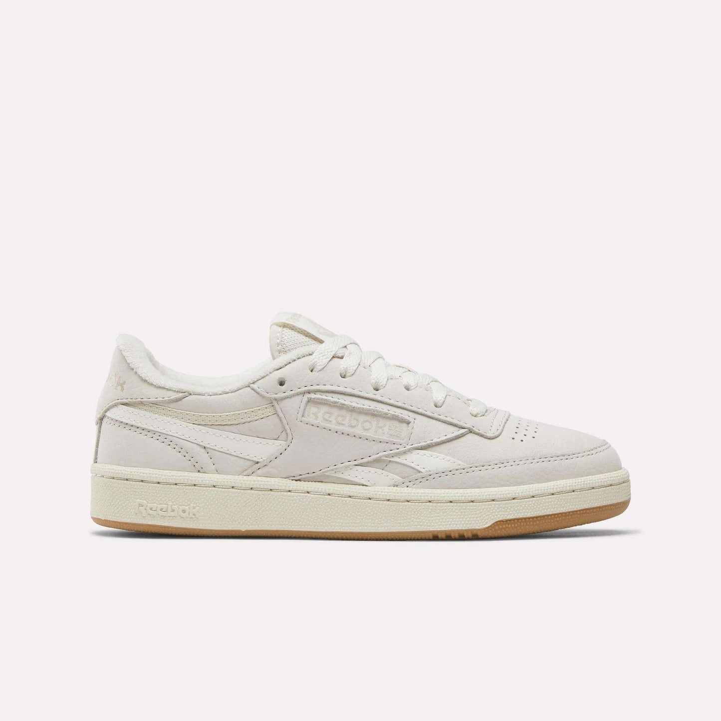 The Reebok Women's Club C Revenge Shoes feature a beige low-top design with a suede and nubuck leather upper, beige laces, and a light brown rubber sole, displayed in side profile on a plain white background.