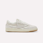 The Reebok Women's Club C Revenge Shoes feature a beige low-top design with a suede and nubuck leather upper, beige laces, and a light brown rubber sole, displayed in side profile on a plain white background.