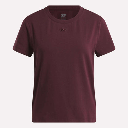 The Women's Graphic Glow Top by Reebok is shown on a white background, featuring a classic maroon design with a small embroidered logo on the chest.