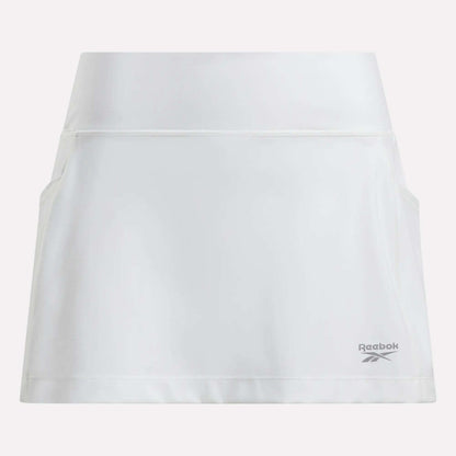 The Women's Break Point Skort by Reebok is plain white with a high waistband, two side pockets, built-in compression shorts, and a small gray Reebok logo near the right hem.
