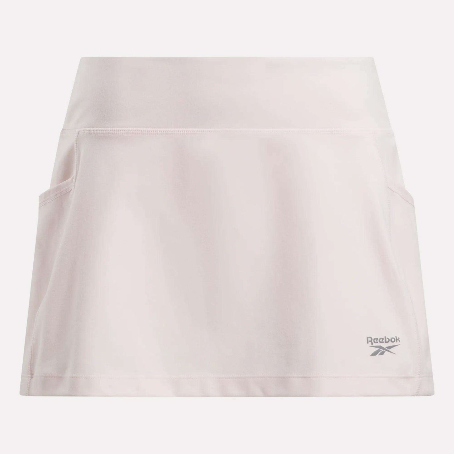 The Reebok Women's Break Point Skort is light pink, features built-in compression shorts, a wide waistband, two side pockets, and the Reebok logo near the right bottom hem.