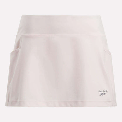 The Reebok Women's Break Point Skort is light pink, features built-in compression shorts, a wide waistband, two side pockets, and the Reebok logo near the right bottom hem.