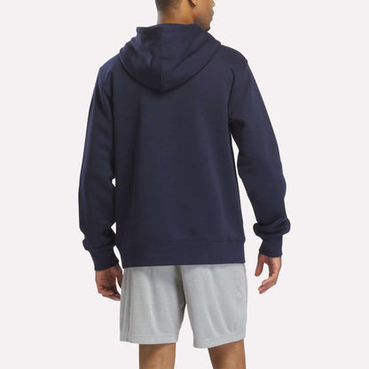 A person is standing and facing away from the camera against a plain background, wearing the Reebok Men's Finisher Hoodie in navy along with light gray shorts.