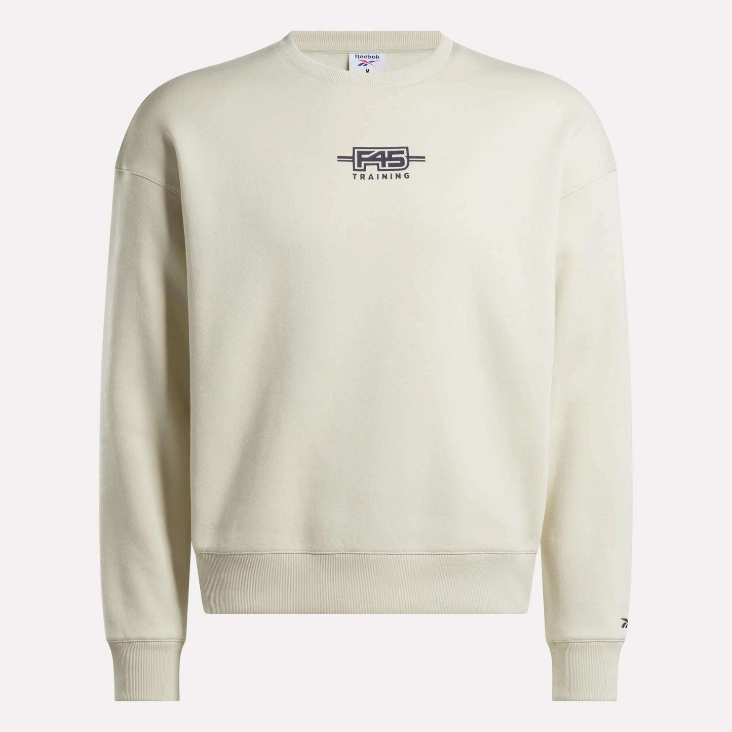 The Reebok x F45 Training Relaxed Graphic Sweatshirt features a cream color, dark F45 TRAINING and barbell logo on the chest, long sleeves, and a relaxed fit—ideal for post-workout lounging.