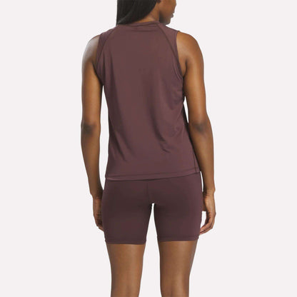 A woman stands facing away, wearing a sleeveless maroon Women's Reebok x F45 Training Tank Top. The background is plain and light-colored.