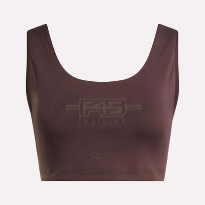Introducing the Women's Reebok x F45 Training Sports Bra. This brown sports bra by Reebok features "F45 Training" embossed on the front, with a subtle Reebok logo beneath. Designed with a scoop neckline and wide shoulder straps, it stands out against a plain background to keep the focus on the garment.