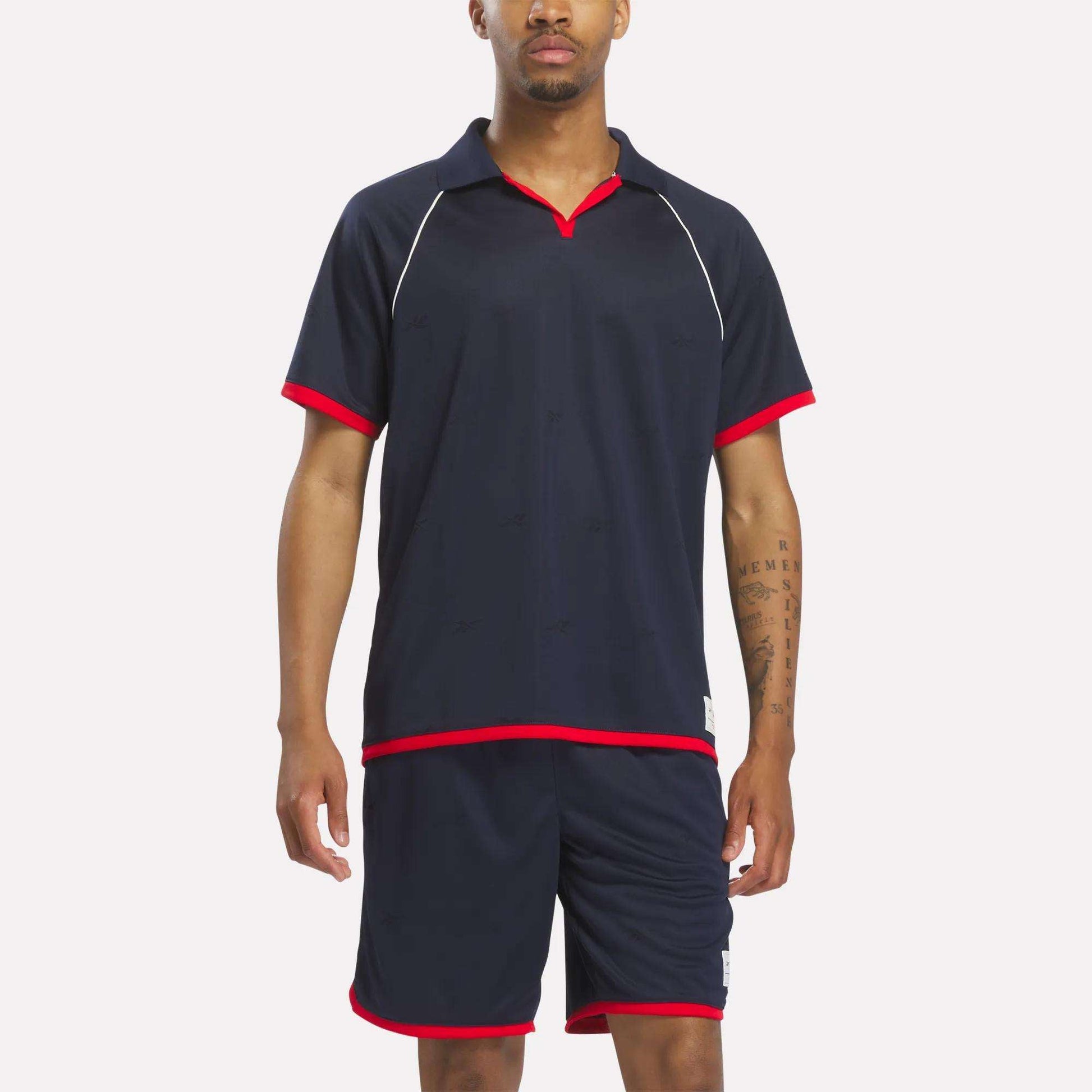 A man stands facing forward against a plain background, wearing a Reebok Men's United Jersey Polo Shirt in Vector Navy.