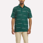 A man models the Reebok Men's Tournament Polo Shirt in Metal Green/White/Black with beige pants against a plain white background, highlighting a tournament-inspired style.