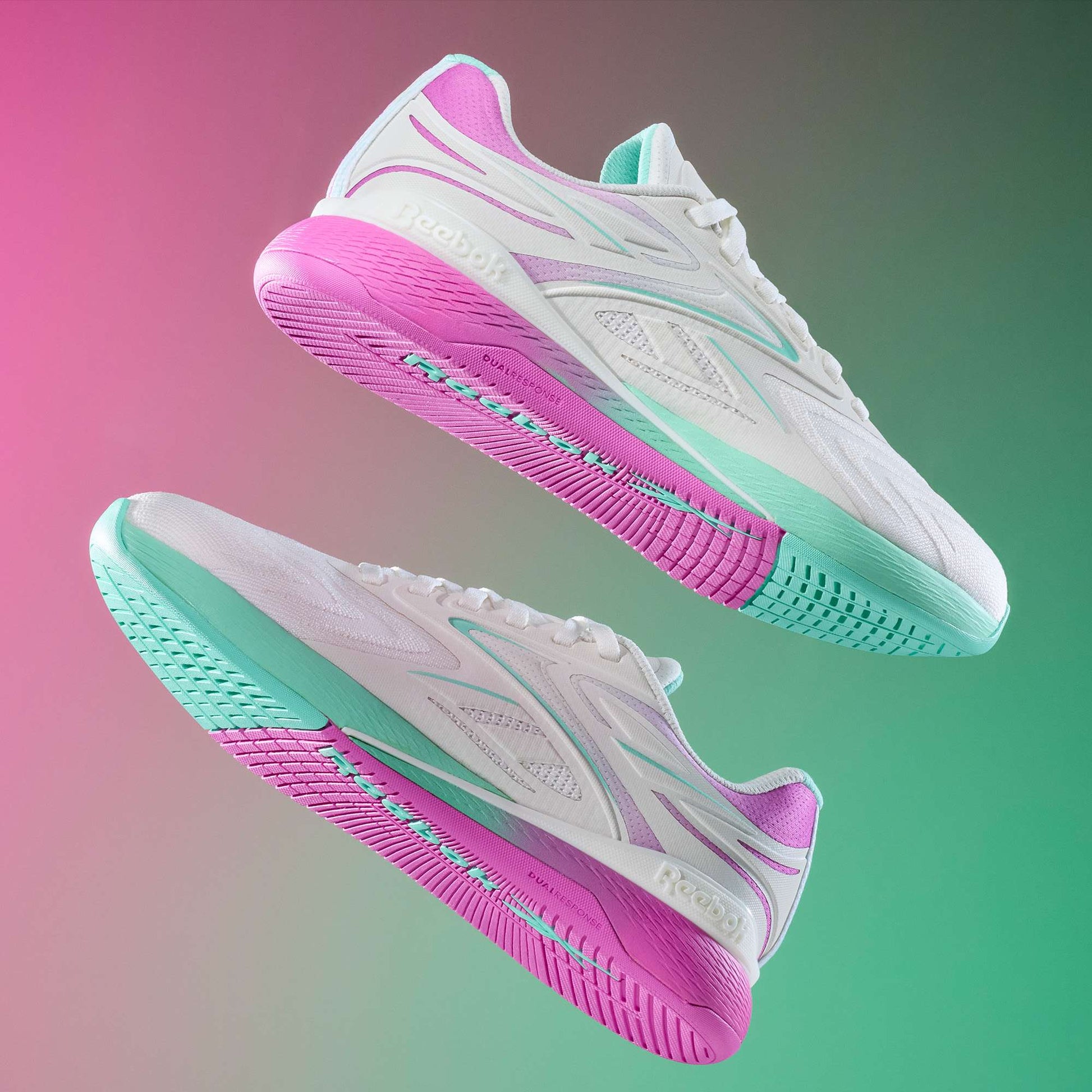 Two white Reebok Women's Nano X5 Edge Training Shoes with pastel pink, purple, and mint green accents float against a pink and green gradient backdrop, highlighting their colorful soles and sleek Reebok design.
