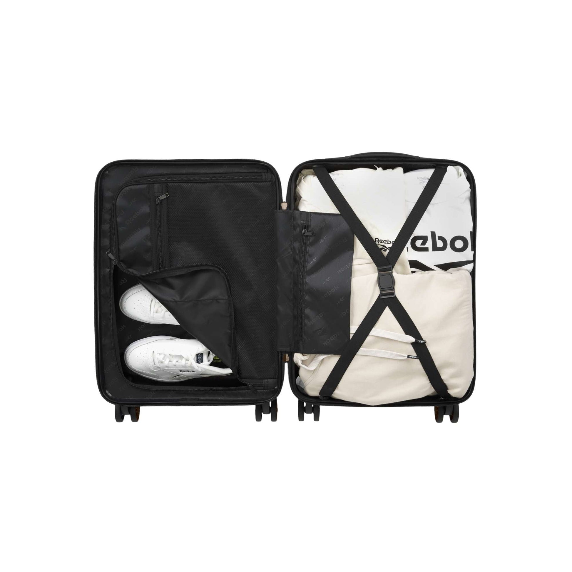 An open Captain 2 Piece Luggage Set by Reebok displays neatly packed items: two white sneakers in a zippered pocket, folded clothes strapped in, and a black interior. The durable luggage set comes with convenient spinner wheels.