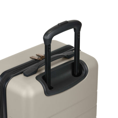 A close-up of the top corner of the beige Reebok Captain 2 Piece Luggage Set, highlighting its black telescopic handle, spinner wheels, and secure zipper with lock.