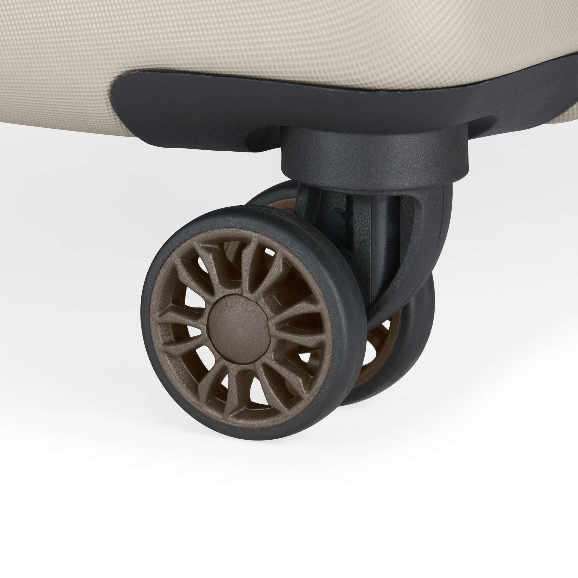 Close-up of a brown spinner wheel on the corner of a beige suitcase from the Reebok Captain 2 Piece Luggage Set, displaying sturdy spokes and durable design—ideal for travelers seeking reliable luggage.