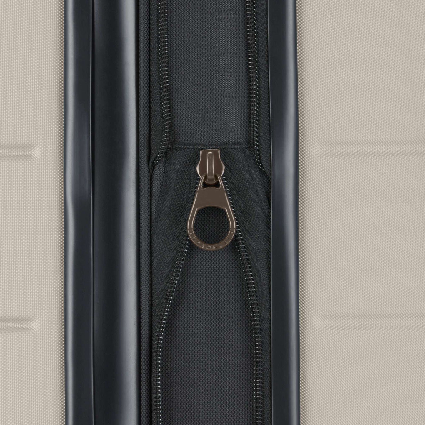 Close-up of a metallic zipper pull on a black zipper against a textured light beige background, featured on the Reebok Captain 2 Piece Luggage Set—a durable choice for travelers.