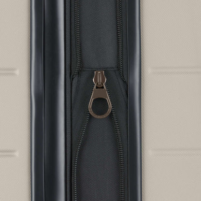 Close-up of a metallic zipper pull on a black zipper against a textured light beige background, featured on the Reebok Captain 2 Piece Luggage Set—a durable choice for travelers.