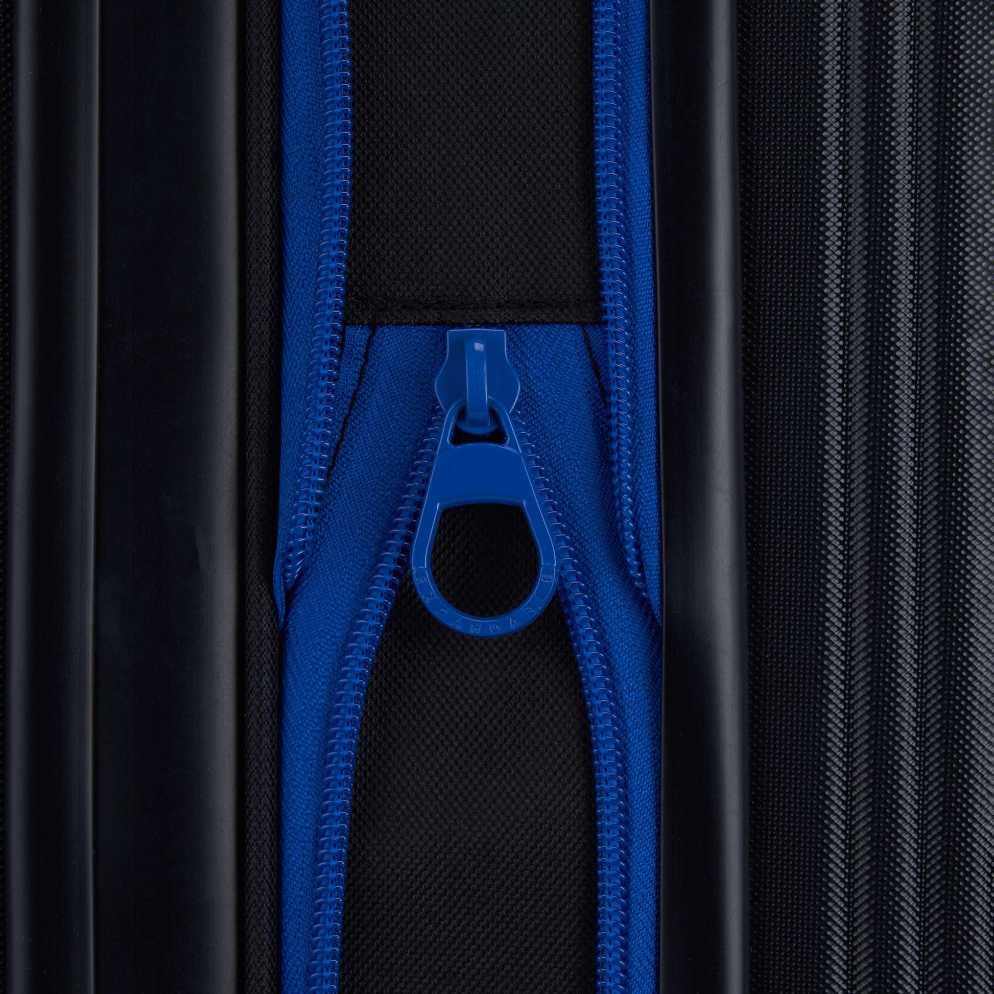Close-up of a blue zipper on black textured fabric from the Reebok Action Duo 2 Piece Luggage Set, with the zipper pulled up and centered in the image.
